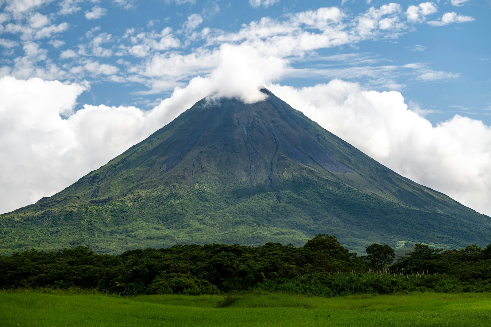 Arenal Volcano cone over green Costa Rican pasture
